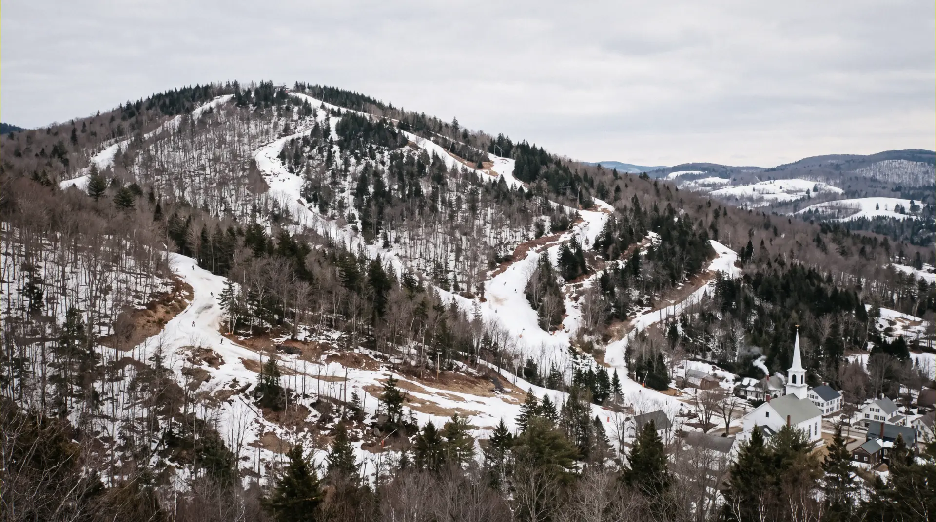 Snow guns working a Vermont trail at first light below a slopeside base, the shortlist for ski-in ski-out lodging in Vermont